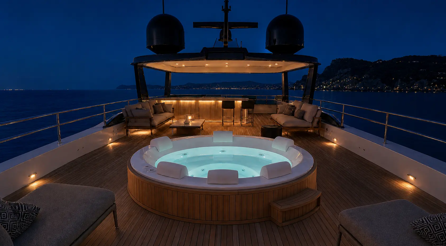Spa circular iluminado no deck durante a noite, com a costa ao fundo